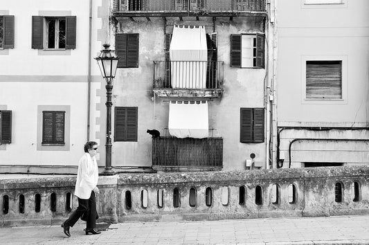 Black and white street photography. Mallorca, Spain. Woman walking, cat about to leap.